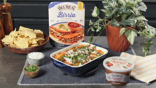 Queso fundido with birria bubbling in a cast iron skillet, with tortilla chips alongside